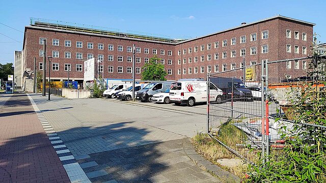 Düsseldorfer Polizeipräsidium aus rotem Backstein, im Vordergrund ein Parkplatz