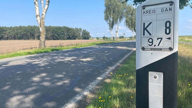 Eigentlich sollte das circa 6 km lange Teilstück der Kreisstraße 8 zwischen Bellahn und Sallahn im niedersächsischen Wendland schon im September 2021 saniert und verbreitert werden. Doch trotz abgeschlossener Planungen und vergebenen Bauauftrags musste der Landkreis das Projekt im Oktober 2022 stoppen. 