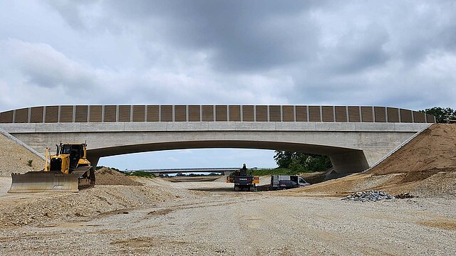 Brückenbauwerk über eine Autobahn, Baustelle mit Baufahrzeugen, Sandberge
