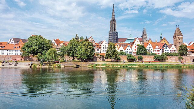 Fluss im Vordergrund, im Hintergrund Stadtansicht von Ulm mit kleiner Flußbrücke